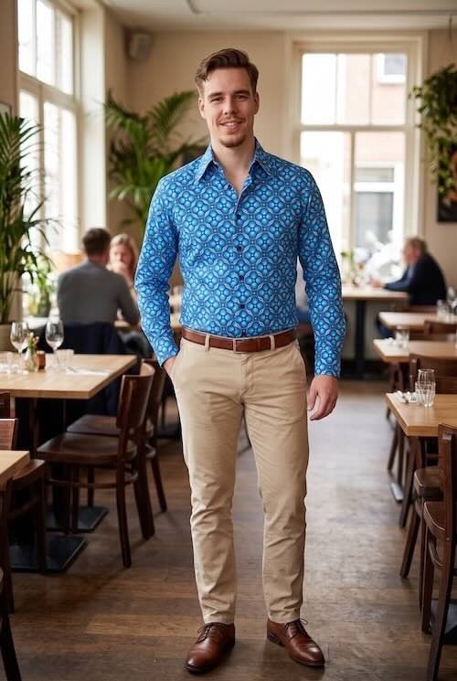 Model draag een blauwe dotsgrid overhemd van Chenaski in zijn lichte broek, hij maakt zijn Smart Casual combinatie af met een bruine riem en schoenen