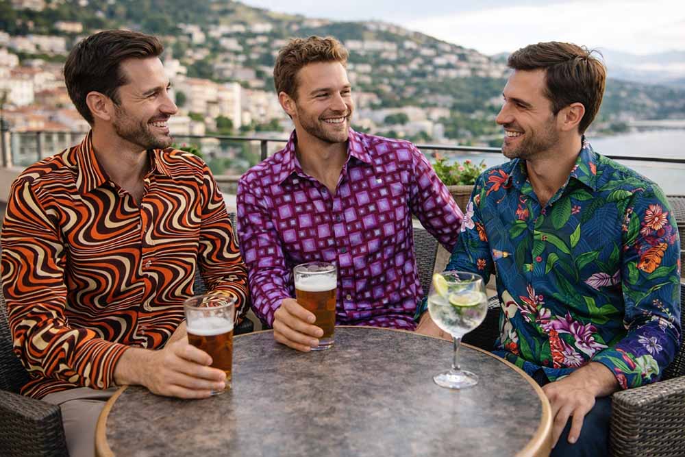 Drie mannen van rond de 35 jaar dragen stijlvolle aparte overhemden op een zonnig terras