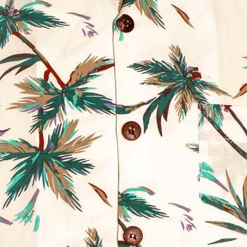 Detailopname van de zomerse palmbladeren print, de bruine knoopjes en het luchtige katoen van het Chenaski overhemd.